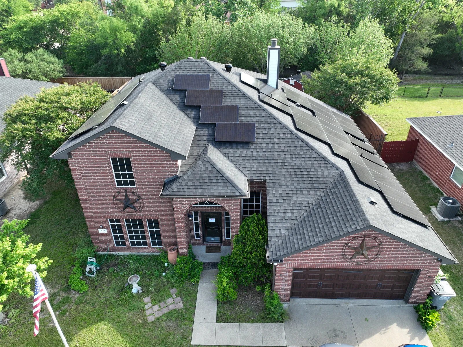 Drone view of a shingle roof on a two-story brick home